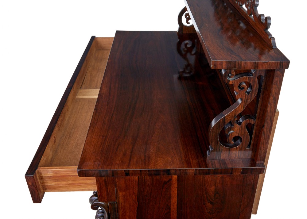 A nineteenth-century Regency palisander chiffonier sideboard with its two panelled doors open, revealing internal wooden shelves, topped with a carved scrollwork gallery shelf. View VIII