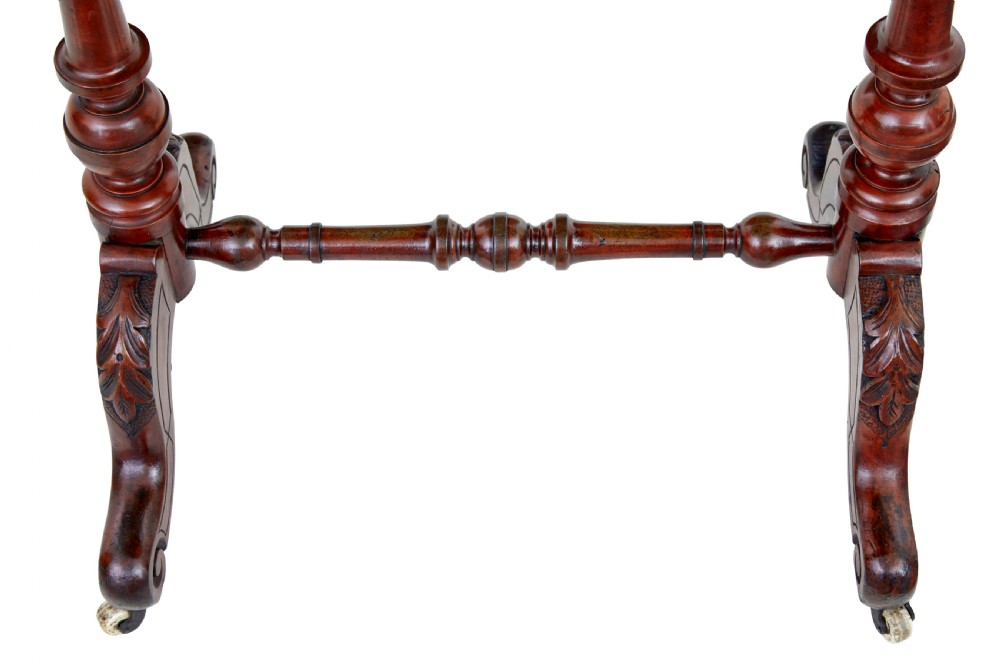 A 19th-century Victorian oval occasional table in polished walnut featuring twin turned support columns, carved legs, a central stretcher, and ceramic castors. View VII