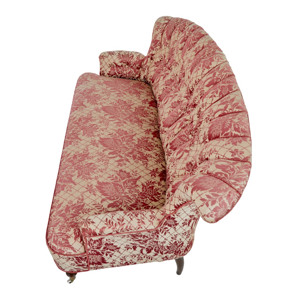 An early 20th century three-piece upholstered salon suite featuring a two-seater settee and two matching armchairs with pink and cream floral damask pattern, button-tufted fluted backs, and turned wooden legs with brass castors. View VII