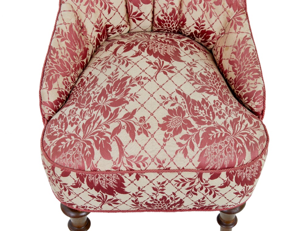 An early 20th century three-piece upholstered salon suite featuring a two-seater settee and two matching armchairs with pink and cream floral damask pattern, button-tufted fluted backs, and turned wooden legs with brass castors. View IX