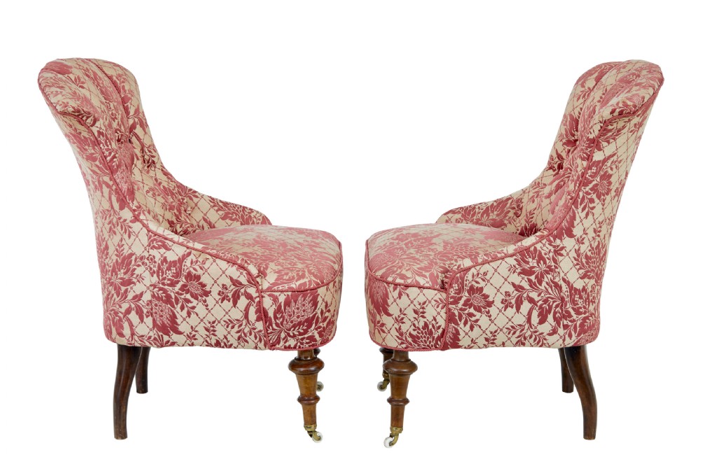 An early 20th century three-piece upholstered salon suite featuring a two-seater settee and two matching armchairs with pink and cream floral damask pattern, button-tufted fluted backs, and turned wooden legs with brass castors. View XIV