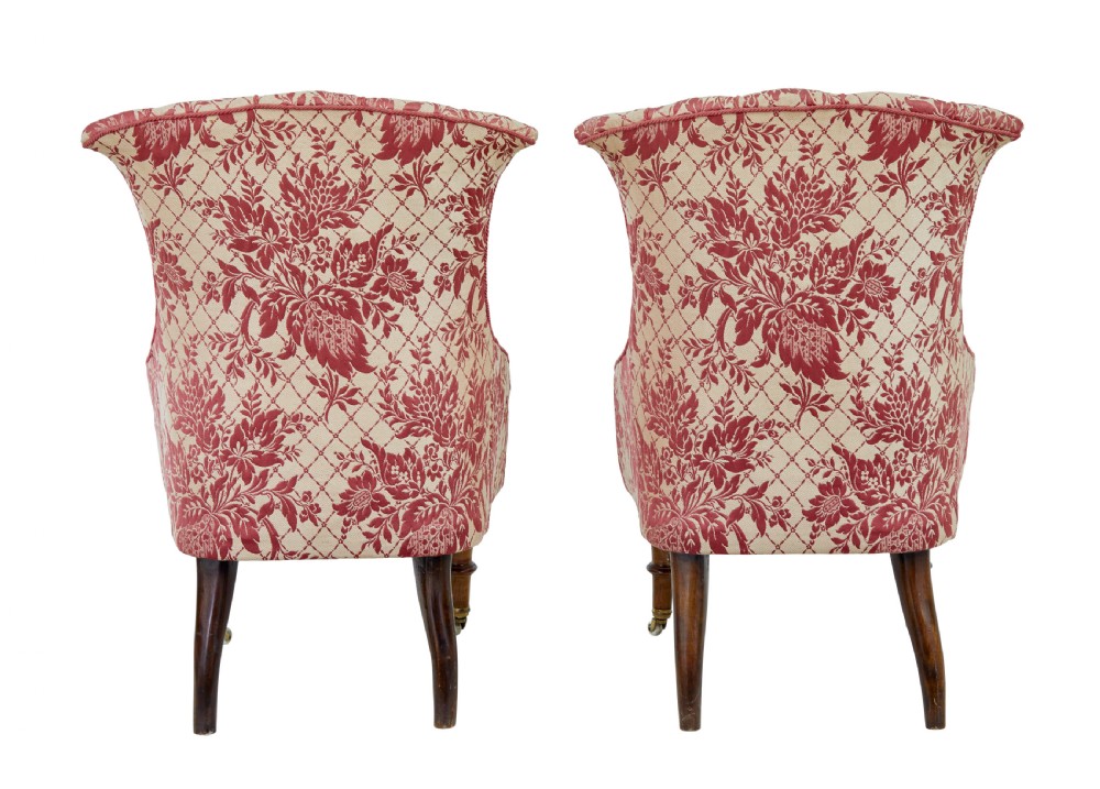 An early 20th century three-piece upholstered salon suite featuring a two-seater settee and two matching armchairs with pink and cream floral damask pattern, button-tufted fluted backs, and turned wooden legs with brass castors. View XV
