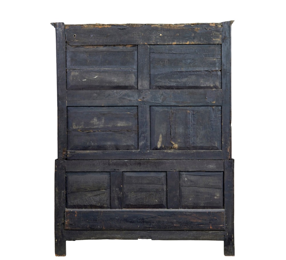 An 18th-century dark oak housekeepers cupboard featuring arched fielded panel doors above a lower section fitted with drawers and brass handles. View III