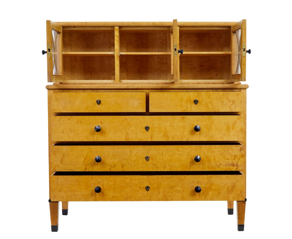A late 19th-century Swedish satin birch cabinet featuring a three-door glazed top section with curved glazing bars resting on a five-drawer chest with dark faceted knobs. View III