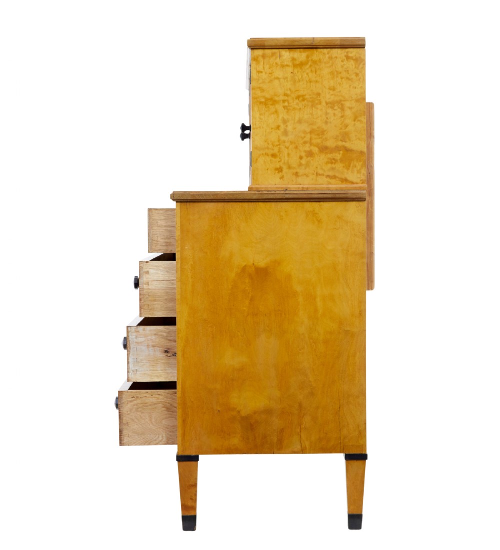A late 19th-century Swedish satin birch cabinet featuring a three-door glazed top section with curved glazing bars resting on a five-drawer chest with dark faceted knobs. View IV
