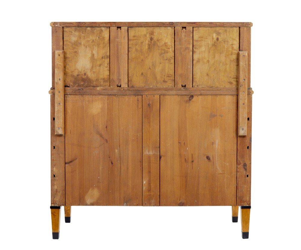 A late 19th-century Swedish satin birch cabinet featuring a three-door glazed top section with curved glazing bars resting on a five-drawer chest with dark faceted knobs. View V