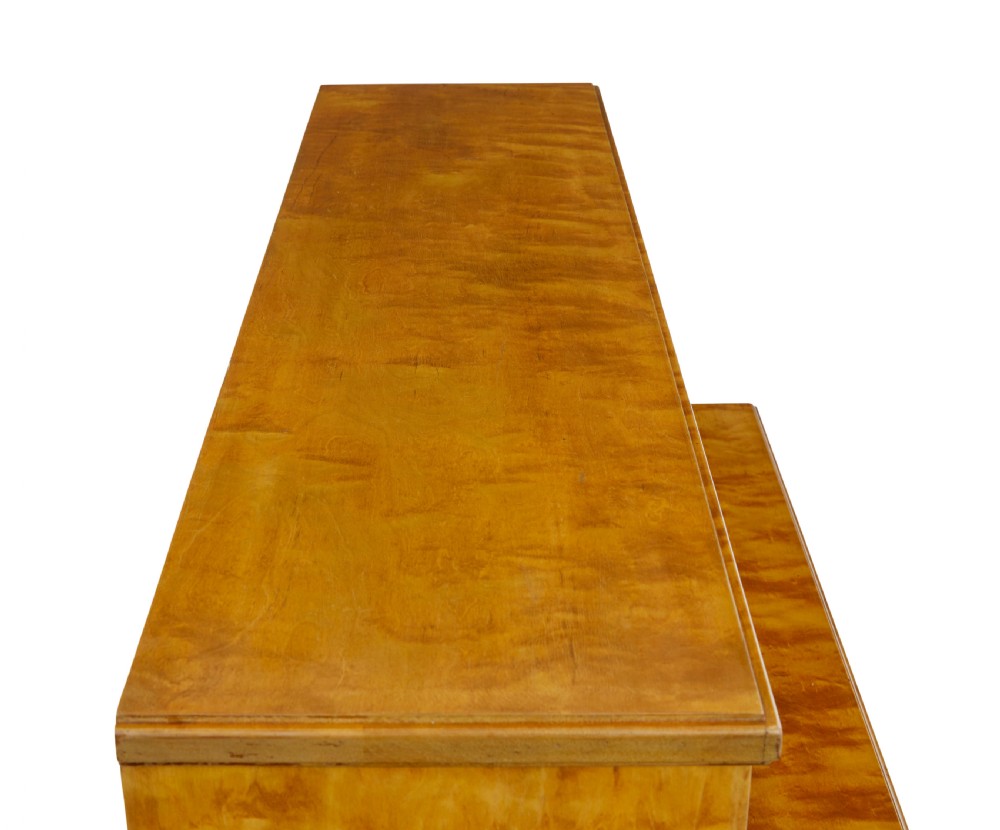 A late 19th-century Swedish satin birch cabinet featuring a three-door glazed top section with curved glazing bars resting on a five-drawer chest with dark faceted knobs. View IX