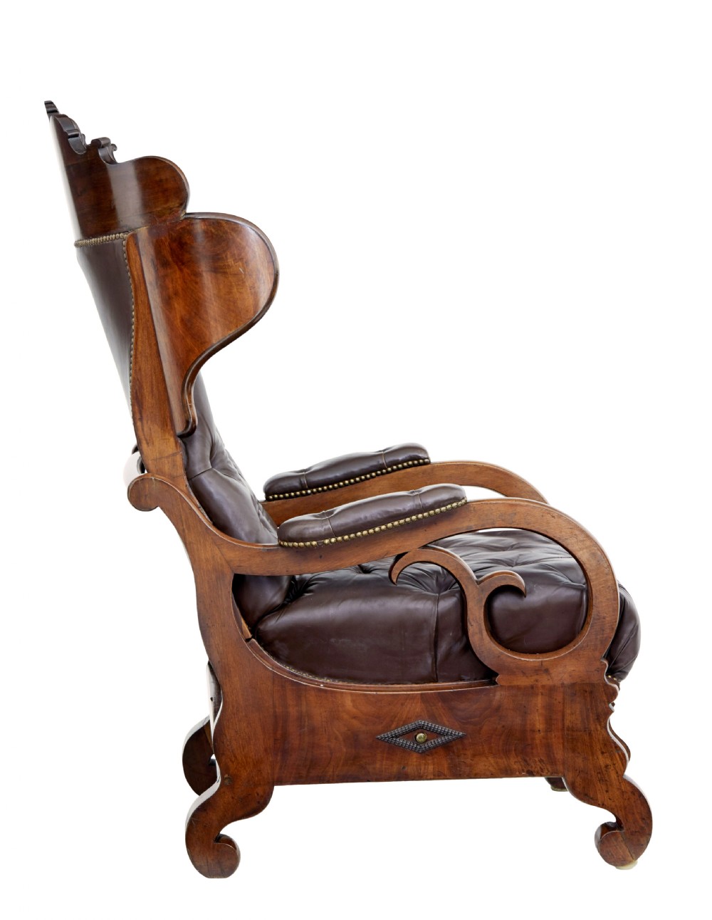A mid-19th-century French reclining armchair featuring carved mahogany scrolled arms, a cresting motif, and deep-buttoned dark brown leather upholstery trimmed with brass studs. View IV