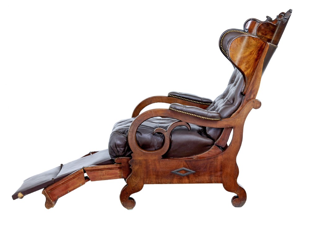 A mid-19th-century French reclining armchair featuring carved mahogany scrolled arms, a cresting motif, and deep-buttoned dark brown leather upholstery trimmed with brass studs. View VII