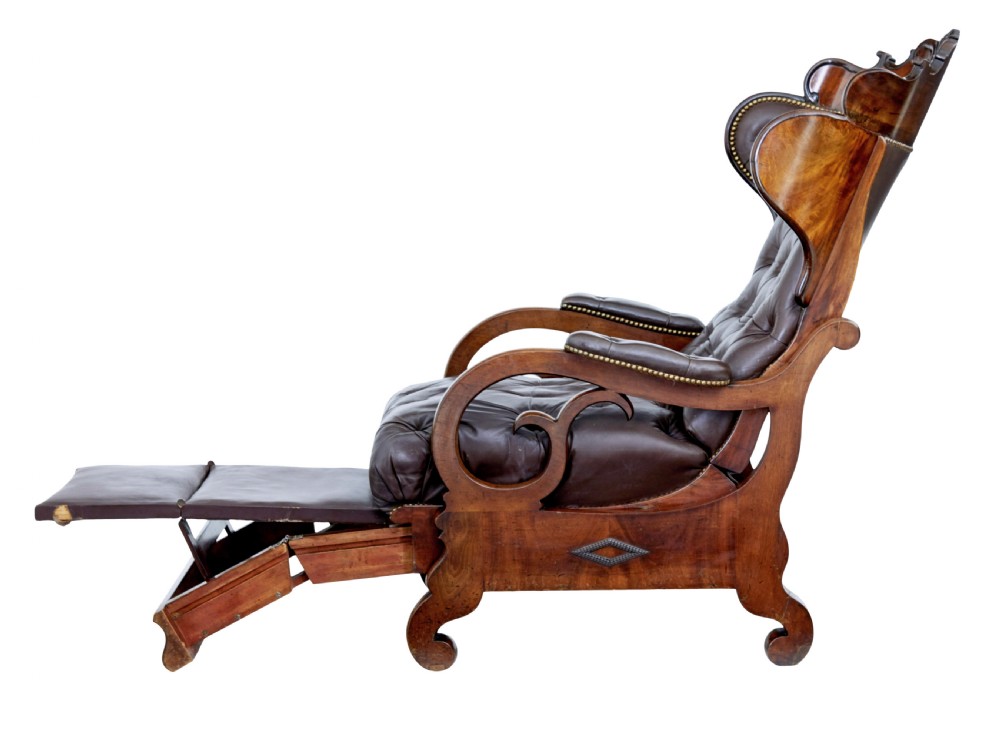 A mid-19th-century French reclining armchair featuring carved mahogany scrolled arms, a cresting motif, and deep-buttoned dark brown leather upholstery trimmed with brass studs. View VIII