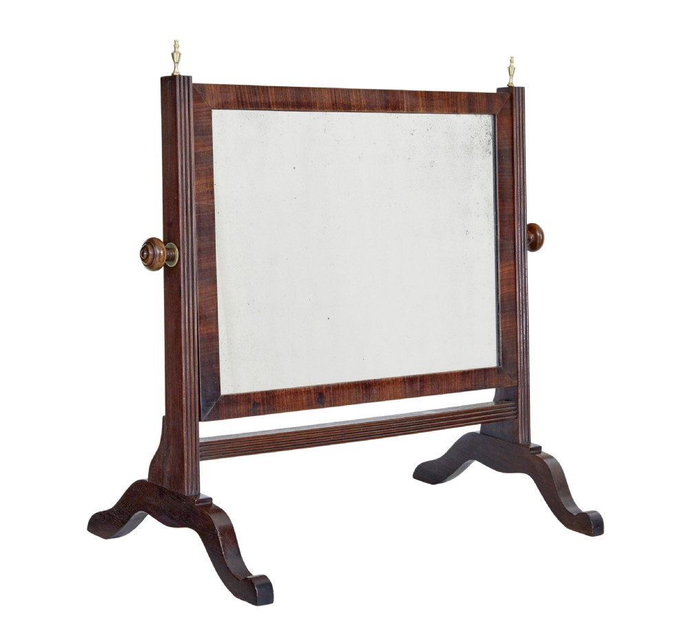 A 19th-century dark mahogany toilet mirror with a rectangular swivelling frame, reeded vertical uprights topped with brass finials, and splayed legs.