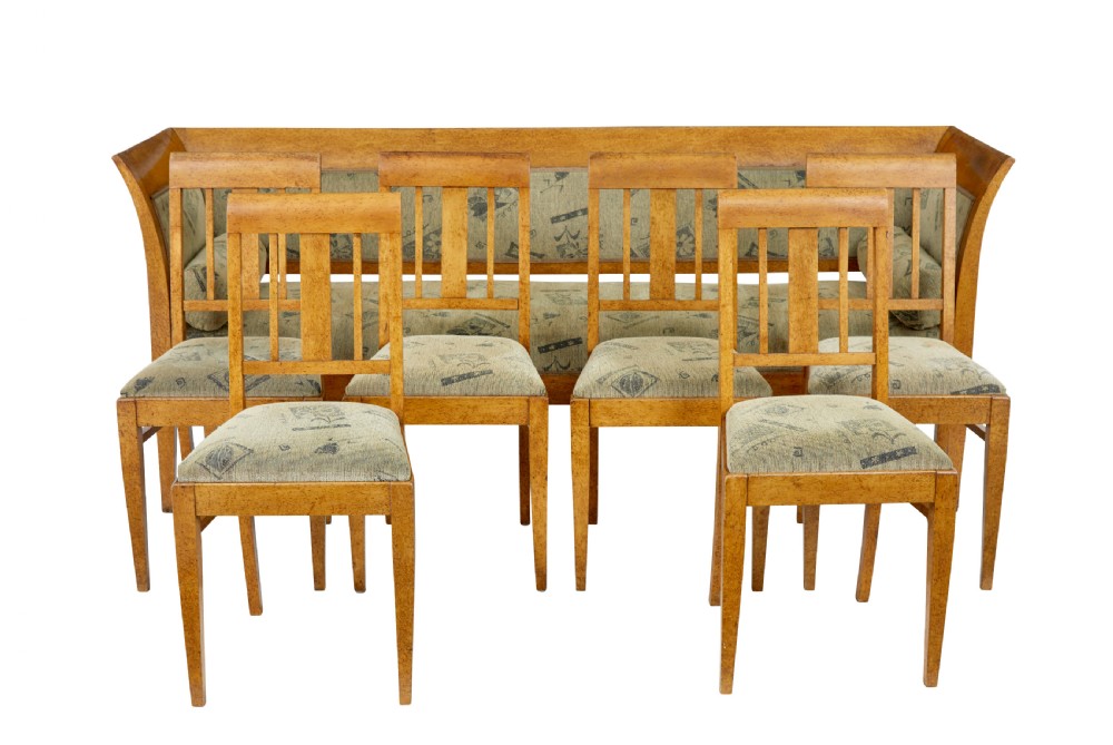 A seven-piece late nineteenth-century seating suite crafted from burr birch timber, including a high-backed sofa and six matching slat-back chairs with patterned fabric seats.