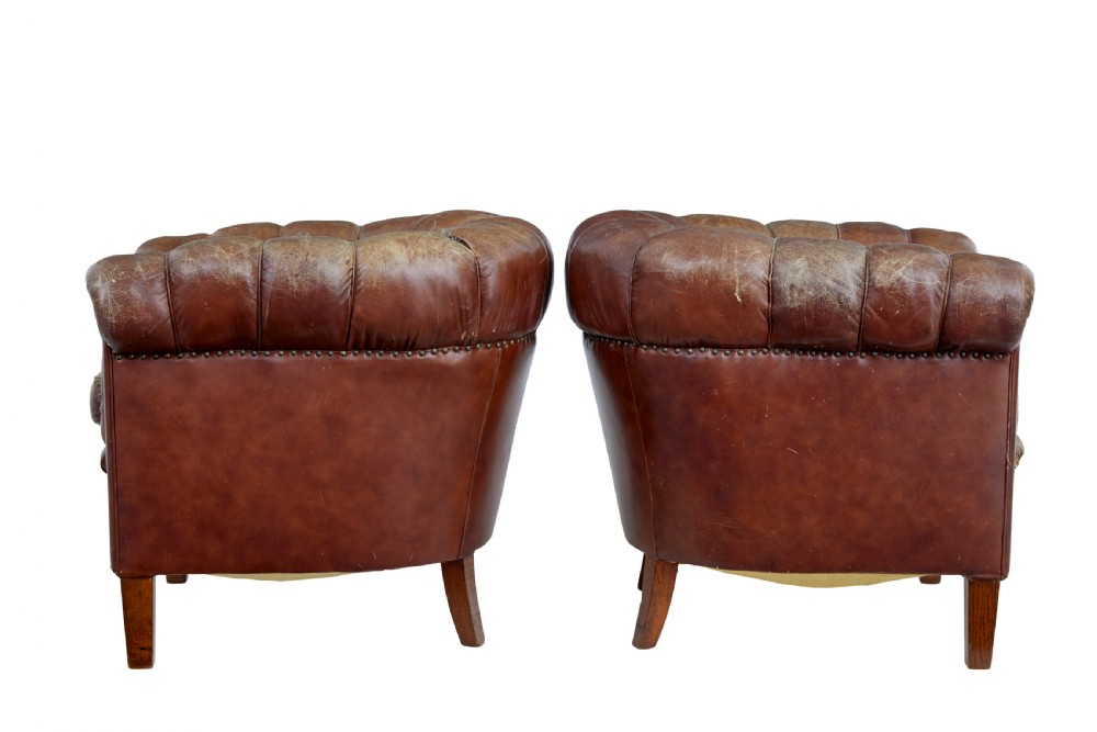 A pair of early 20th-century brown leather club armchairs with deep buttoning, rolled arms, loose seat cushions, and square timber legs. View II