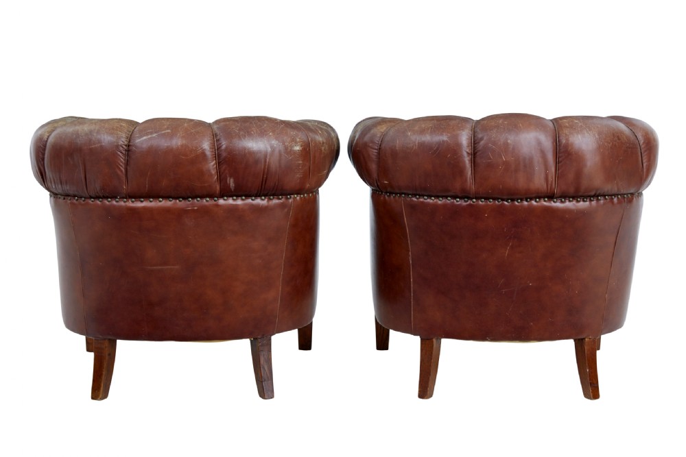 A pair of early 20th-century brown leather club armchairs with deep buttoning, rolled arms, loose seat cushions, and square timber legs. View III