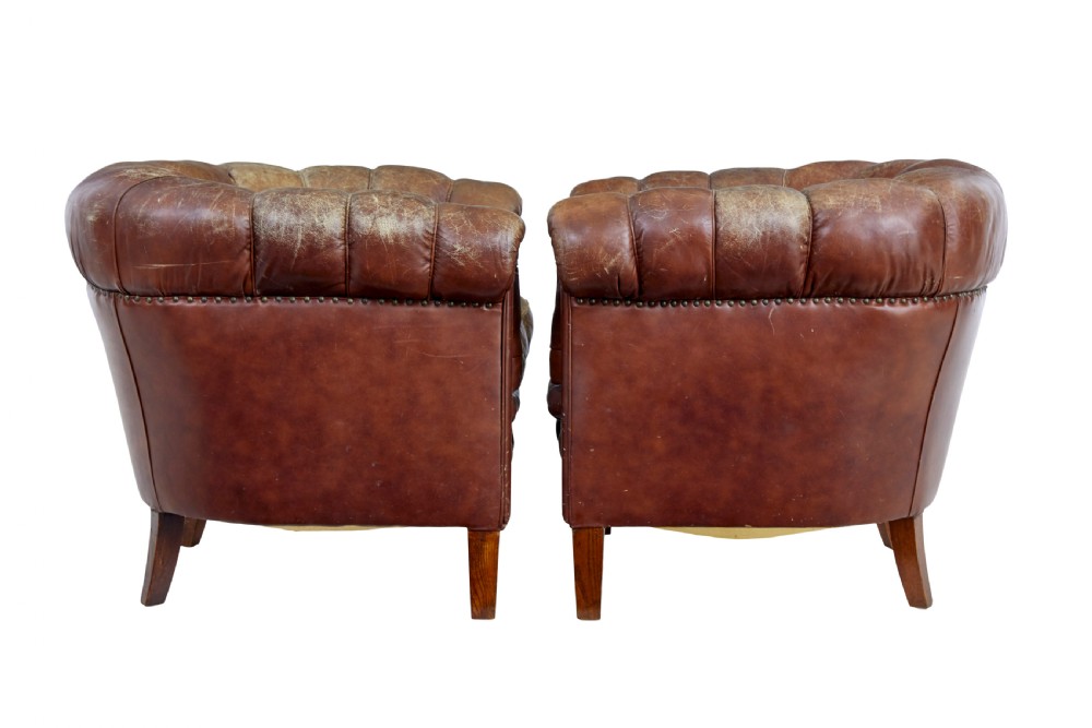A pair of early 20th-century brown leather club armchairs with deep buttoning, rolled arms, loose seat cushions, and square timber legs. View IV