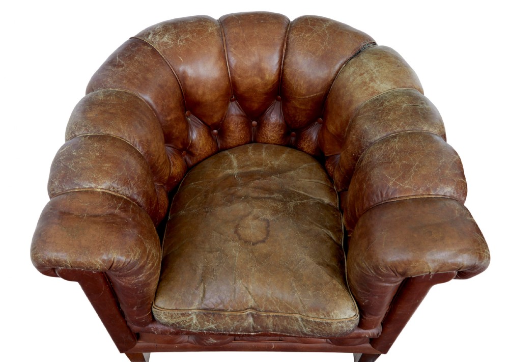 A pair of early 20th-century brown leather club armchairs with deep buttoning, rolled arms, loose seat cushions, and square timber legs. View V