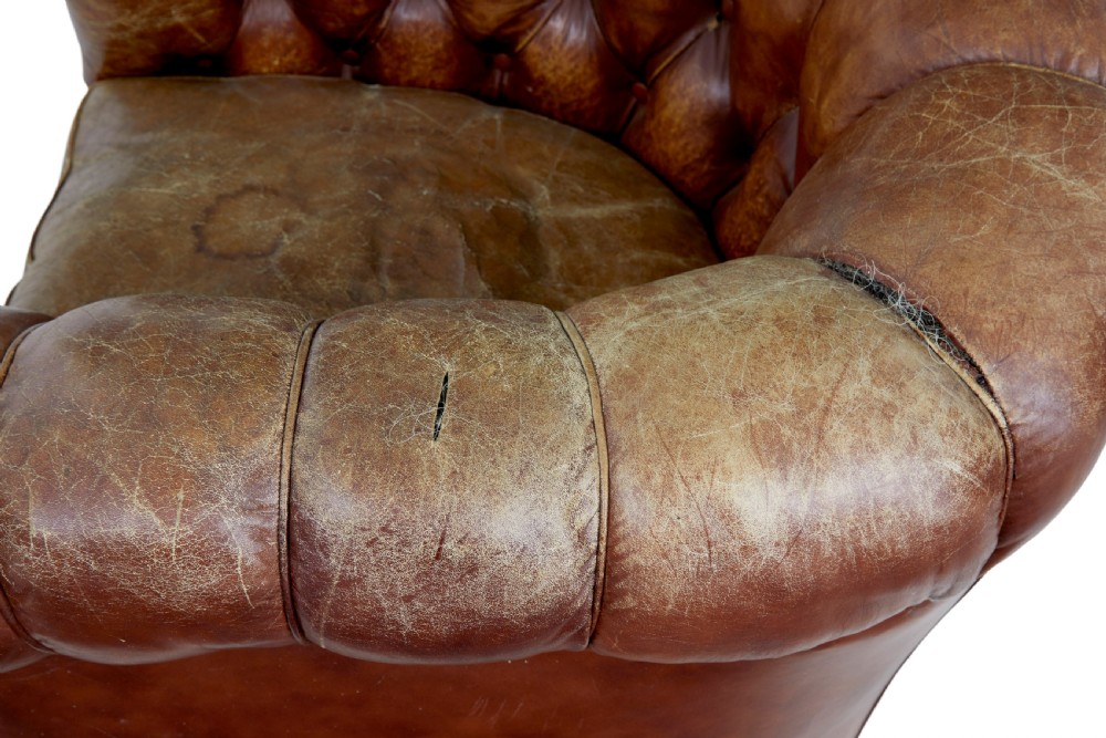 A pair of early 20th-century brown leather club armchairs with deep buttoning, rolled arms, loose seat cushions, and square timber legs. View VI