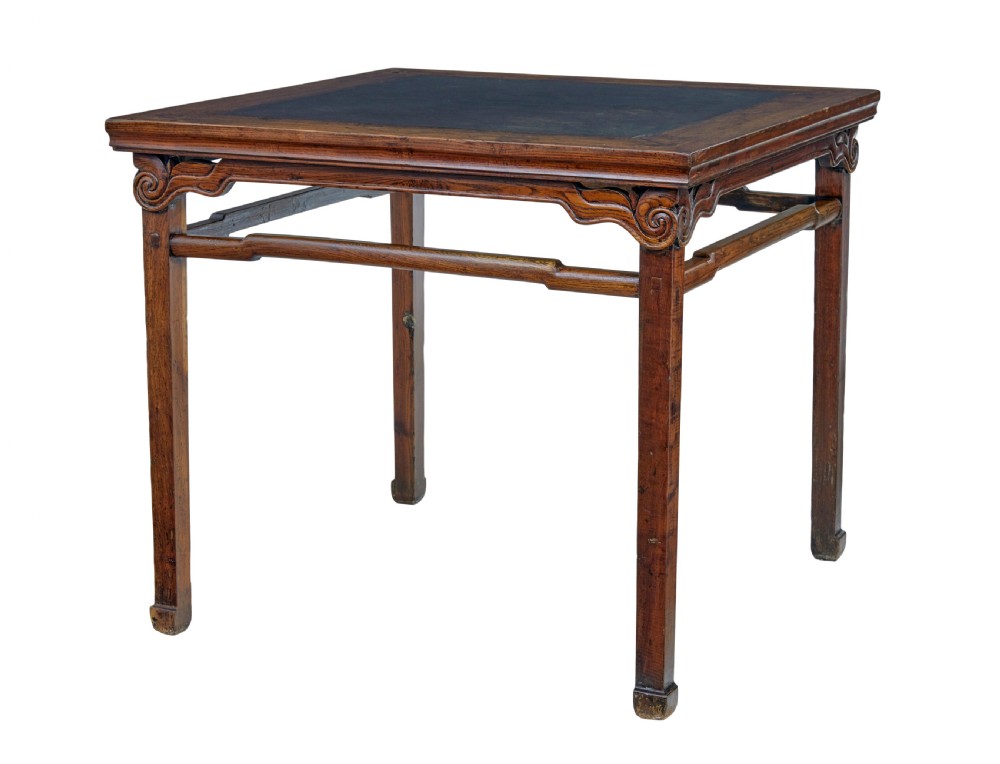 A 19th-century square Chinese hardwood centre table with an inset dark marble top, carved scroll spandrels, and humpback stretchers.