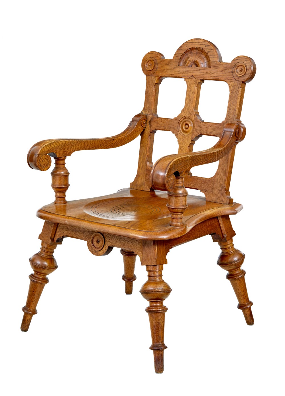 A late 19th-century carved oak armchair featuring a geometric openwork backrest with roundel details, turned legs, and sweeping wooden armrests.