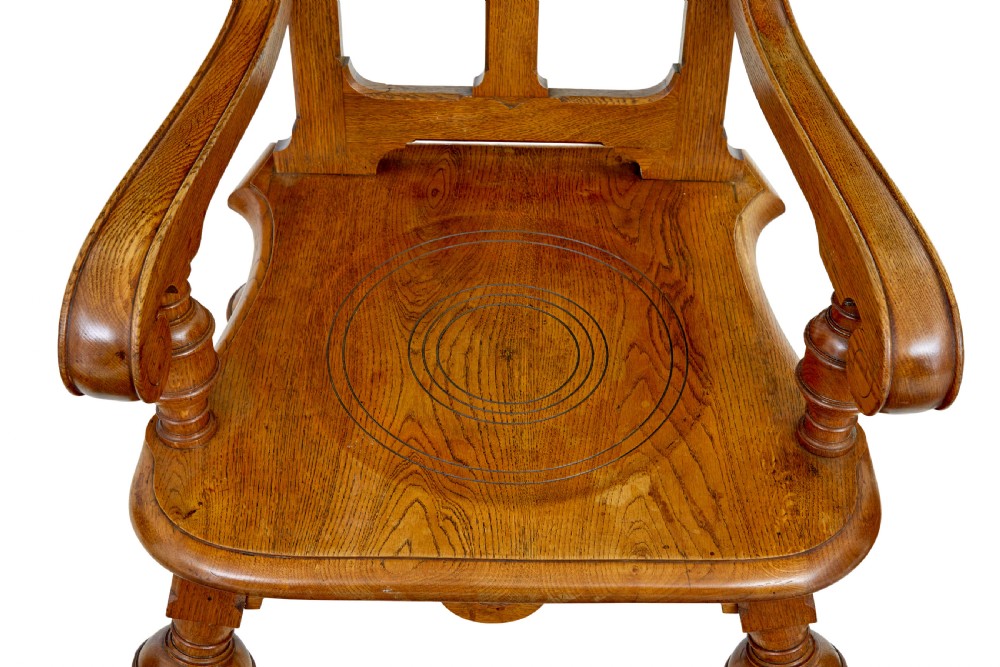 A late 19th-century carved oak armchair featuring a geometric openwork backrest with roundel details, turned legs, and sweeping wooden armrests. View II