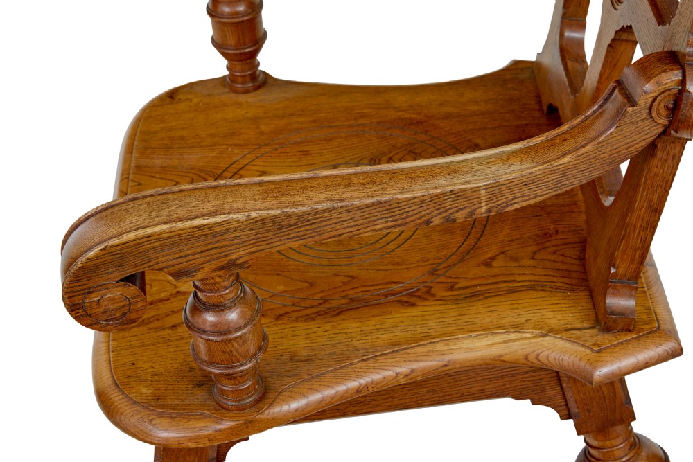 A late 19th-century carved oak armchair featuring a geometric openwork backrest with roundel details, turned legs, and sweeping wooden armrests. View IV