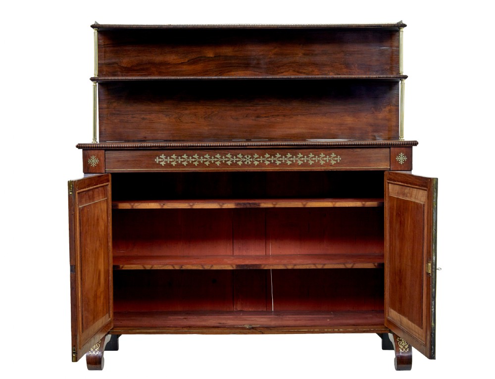 A 19th-century Regency palisander chiffonier with brass inlay, a two-tier raised shelf back supported by brass columns, and green pleated fabric door panels. View II