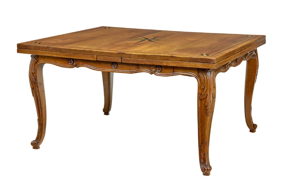 A 19th-century French fruitwood extending dining table with carved cabriole legs and a star inlay motif on the rectangular top.