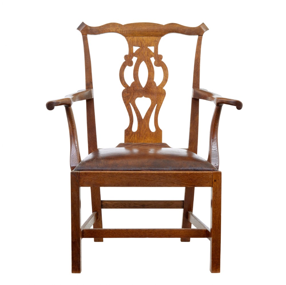 A 19th-century solid oak armchair featuring shepherds crook armrests, a carved pierced back splat, and a brown leather seat cushion. View II
