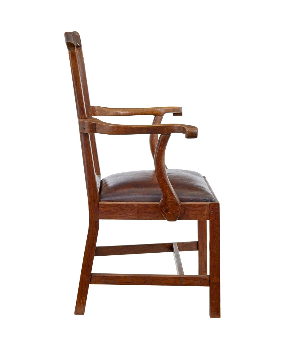 A 19th-century solid oak armchair featuring shepherds crook armrests, a carved pierced back splat, and a brown leather seat cushion. View IV
