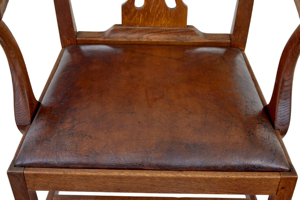 A 19th-century solid oak armchair featuring shepherds crook armrests, a carved pierced back splat, and a brown leather seat cushion. View VII