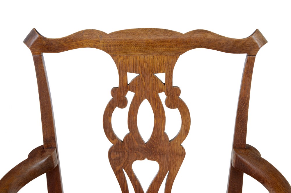 A 19th-century solid oak armchair featuring shepherds crook armrests, a carved pierced back splat, and a brown leather seat cushion. View VIII
