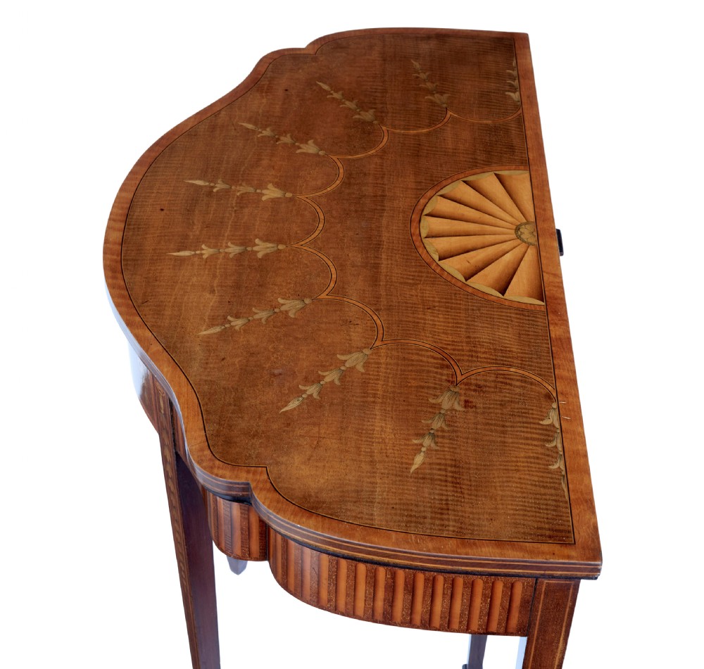 A 19th-century Sheraton Revival mahogany card table featuring a demi-lune fold-over top, satinwood marquetry with urn and swag motifs, and four tapered square legs. View II