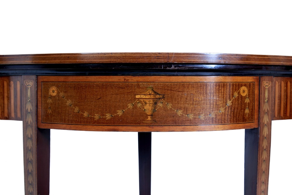 A 19th-century Sheraton Revival mahogany card table featuring a demi-lune fold-over top, satinwood marquetry with urn and swag motifs, and four tapered square legs. View V