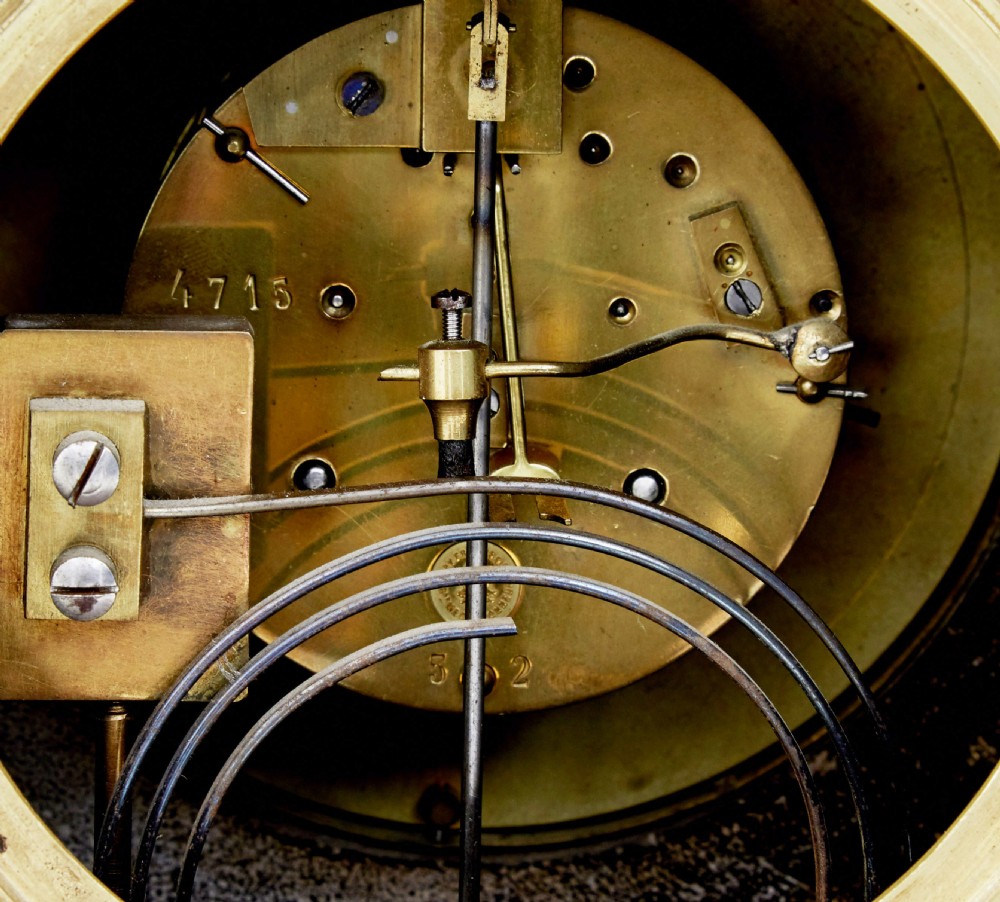A High Victorian black marble mantel clock featuring gold incised scrollwork, a classical cherub relief panel, and a central circular dial with Roman numerals. View V