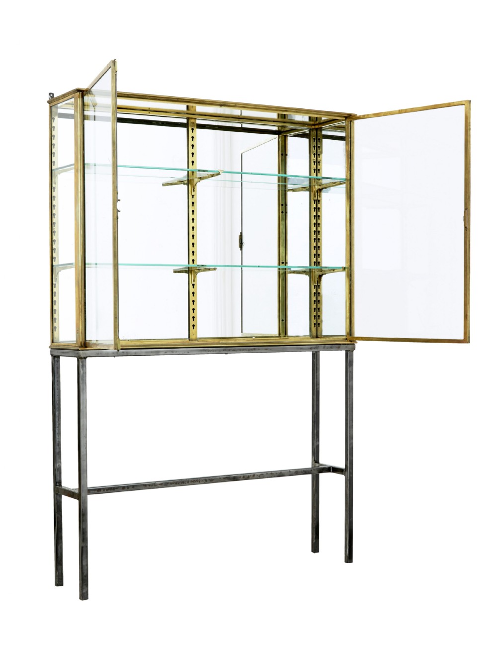 A 1920s French brass glazed display cabinet by Siegel resting on a tall dark steel base with adjustable internal glass shelves. View II