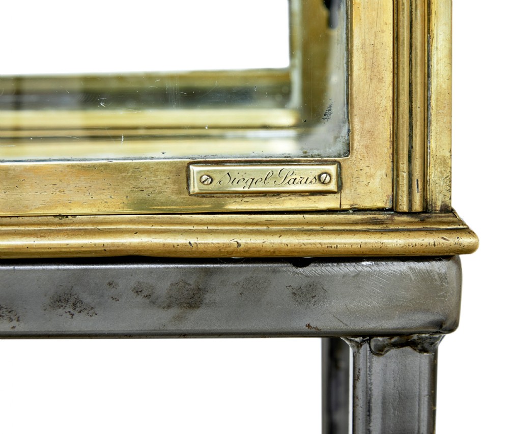 A 1920s French brass glazed display cabinet by Siegel resting on a tall dark steel base with adjustable internal glass shelves. View III
