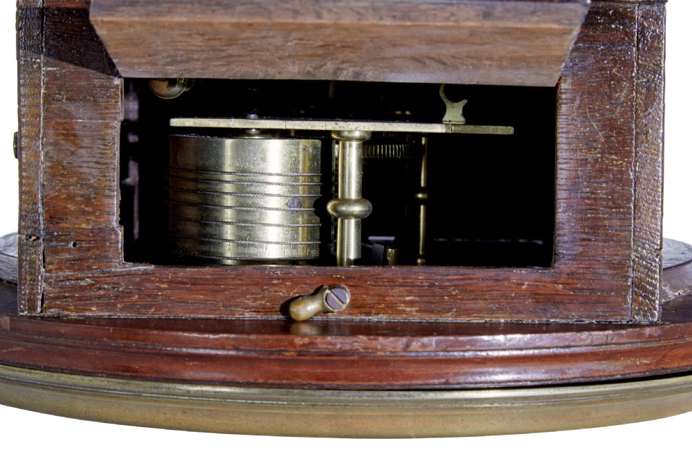 An 18th-century Georgian wall clock featuring an engraved silvered dial with Roman numerals, a brass bezel, and a circular mahogany surround. View VIII