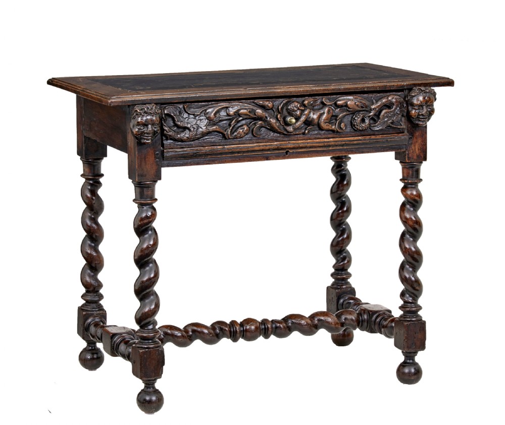 An early 19th-century Flemish carved walnut side table featuring barley twist legs, a carved frieze drawer with corner masks, and a low twist stretcher.
