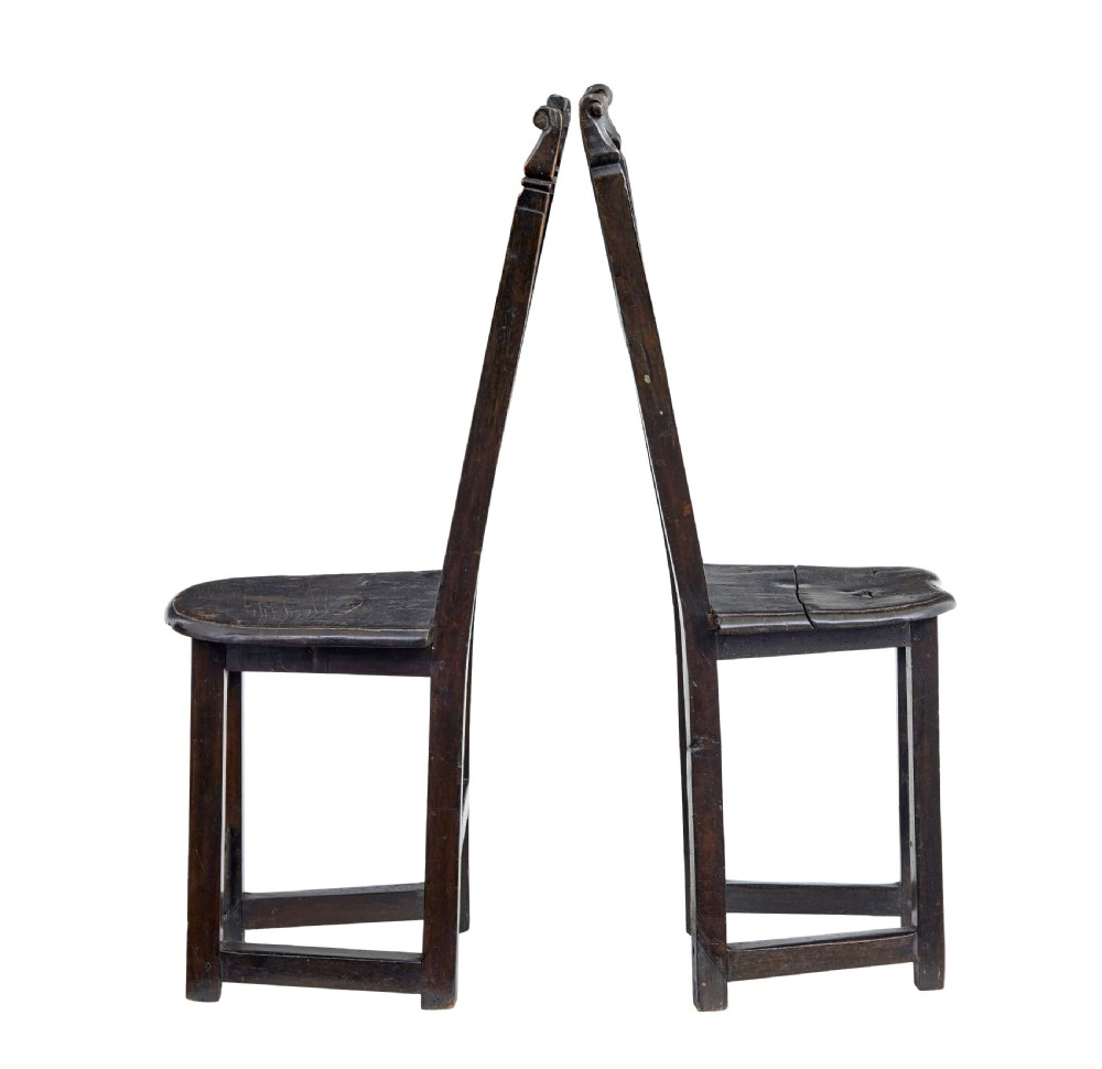 A pair of 19th-century dark oak Carolean-inspired hall chairs featuring intricate scrollwork carving, inlaid back panels, and turned finials. View II