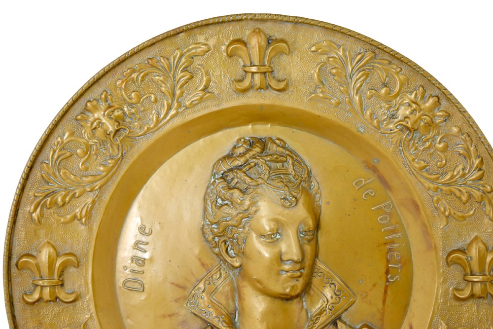 A pair of circular 19th-century French brass wall sconces featuring central relief portraits of Diane de Poitiers and King Francois I, adorned with fleur-de-lis motifs and three candle branches each. View V