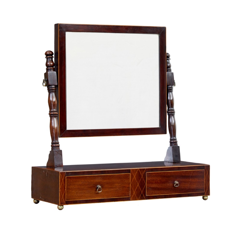 An antique Victorian mahogany toilet mirror with a rectangular tilting glass plate supported by turned upright pillars above a two-drawer inlaid base.
