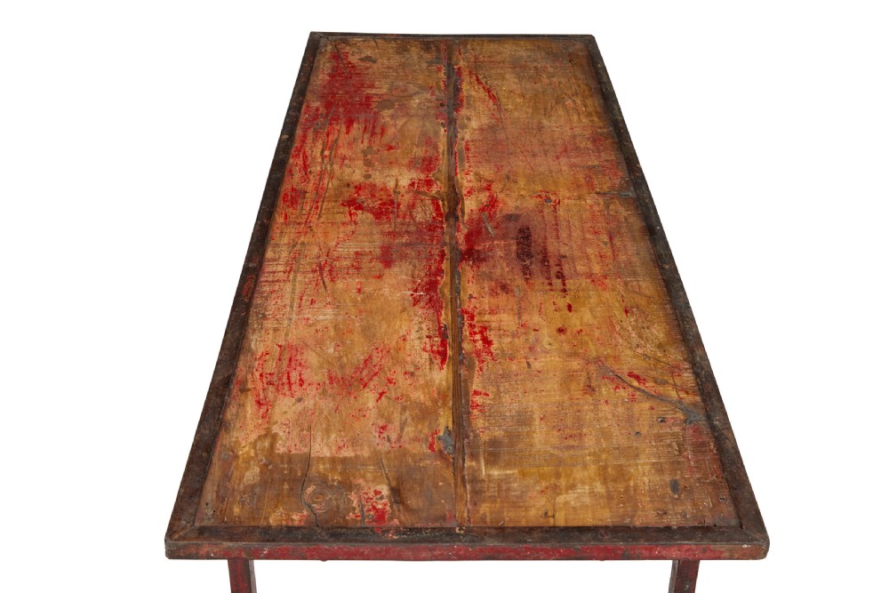 A rectangular folding table featuring a weathered wood top set within a distressed red-painted metal frame and leg structure. View VI