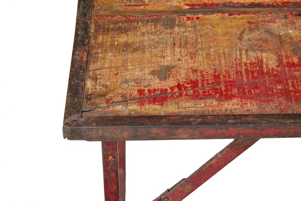 A rectangular folding table featuring a weathered wood top set within a distressed red-painted metal frame and leg structure. View VIII