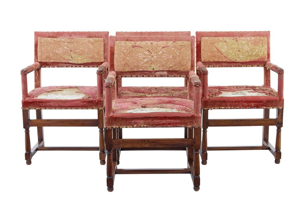 A set of 19th-century carved walnut armchairs with worn red velvet upholstery and embroidered decorative backrest panels.