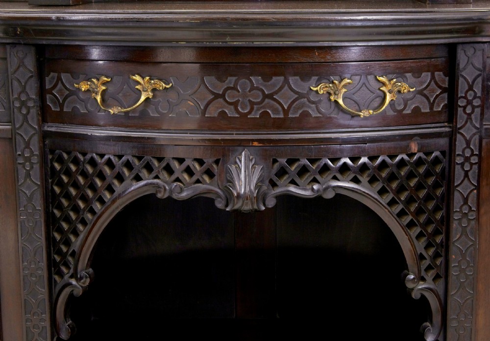 An Edwardian Chippendale Revival dark mahogany display cabinet featuring a multi-paneled mirrored upper section, carved crest, fretwork, and glazed side doors on cabriole legs. View VII