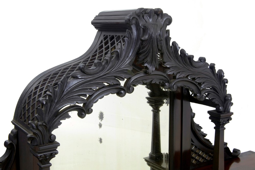 An Edwardian Chippendale Revival dark mahogany display cabinet featuring a multi-paneled mirrored upper section, carved crest, fretwork, and glazed side doors on cabriole legs. View VIII