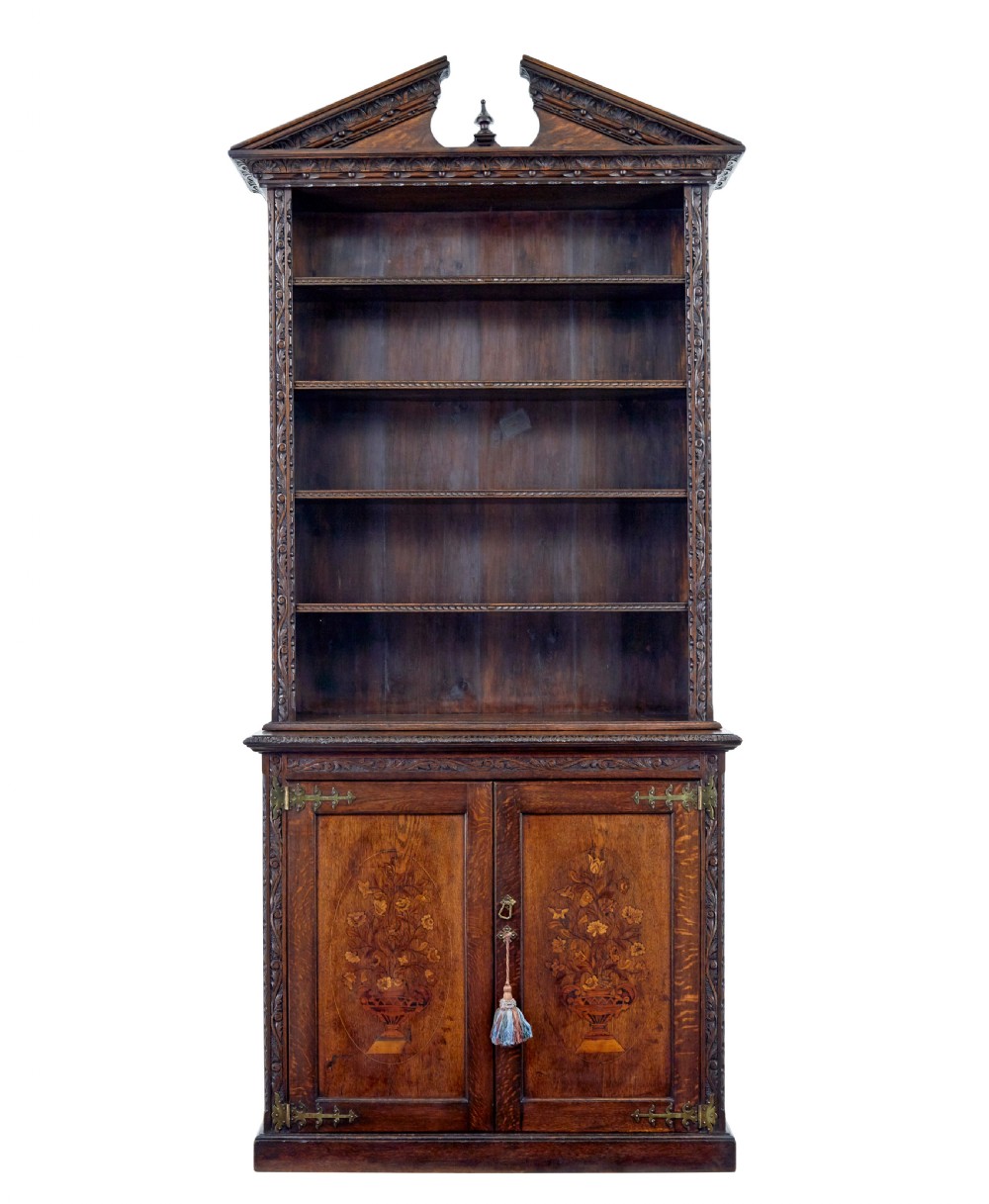A 19th-century dark oak architectural cabinet featuring an open upper shelf section with a broken pediment crown and lower cupboard doors adorned with floral marquetry inlay.