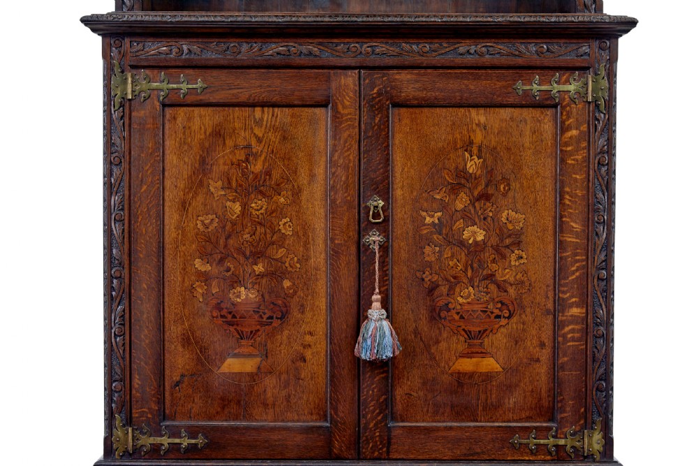 A 19th-century dark oak architectural cabinet featuring an open upper shelf section with a broken pediment crown and lower cupboard doors adorned with floral marquetry inlay. View VII