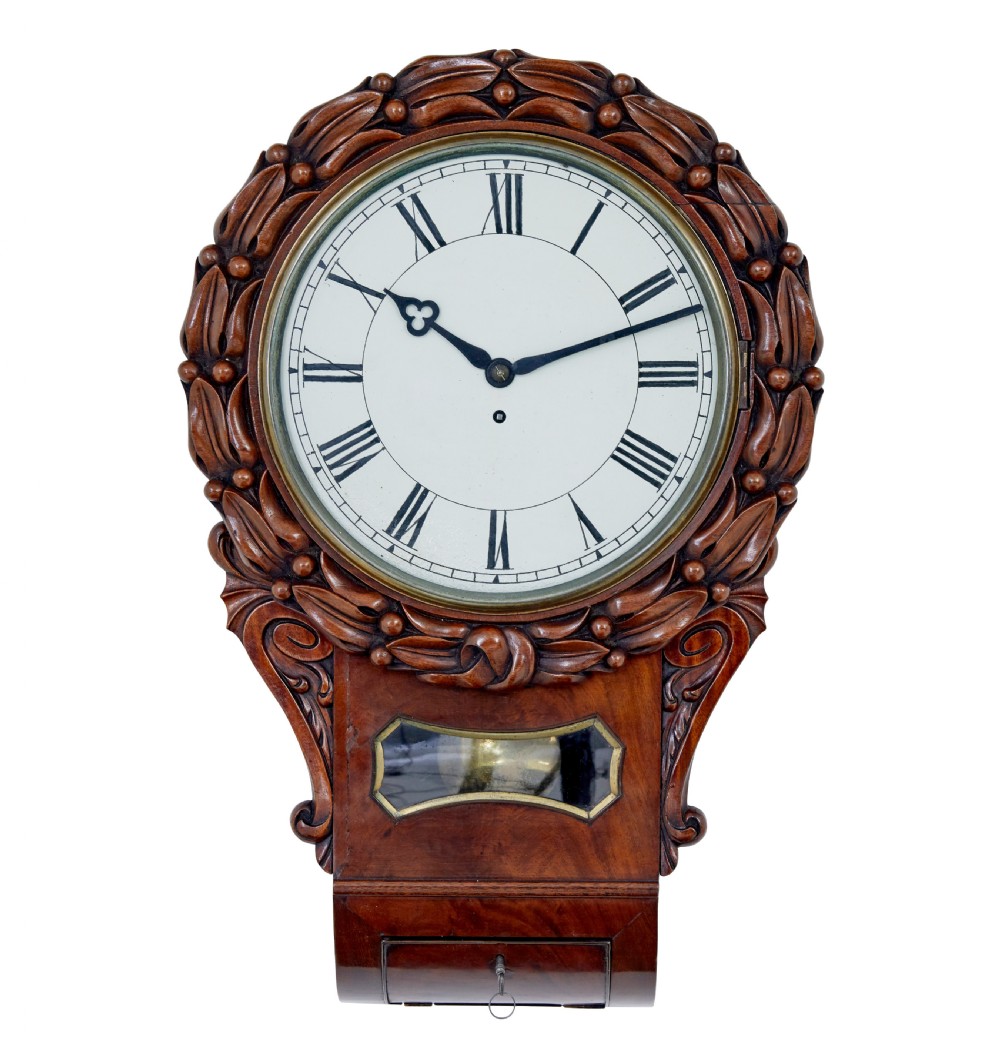 A mid-19th century Victorian mahogany fusee wall clock featuring a hand-carved foliate surround, white dial with Roman numerals, and a lower pendulum window.