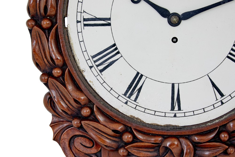 A mid-19th century Victorian mahogany fusee wall clock featuring a hand-carved foliate surround, white dial with Roman numerals, and a lower pendulum window. View III